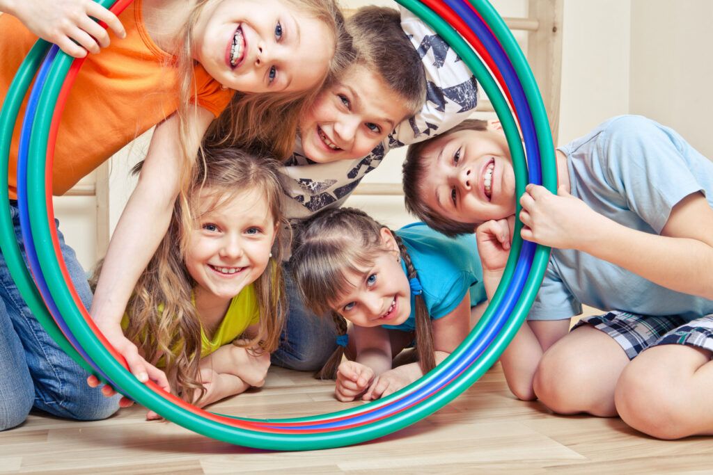Fünf glückliche Kinder schauen durch einen Hula Hoop.