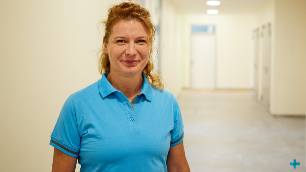 Porträt von Annett Velebil, der Leiterin des Rudolf Virchow Gesundheitszentrums, lächelnd in einem hellen Flur.