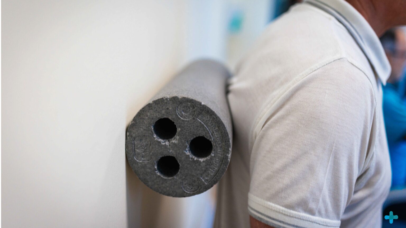 Mann nutzt graue Faszienrolle an einer Wand für Rücken-Faszientraining