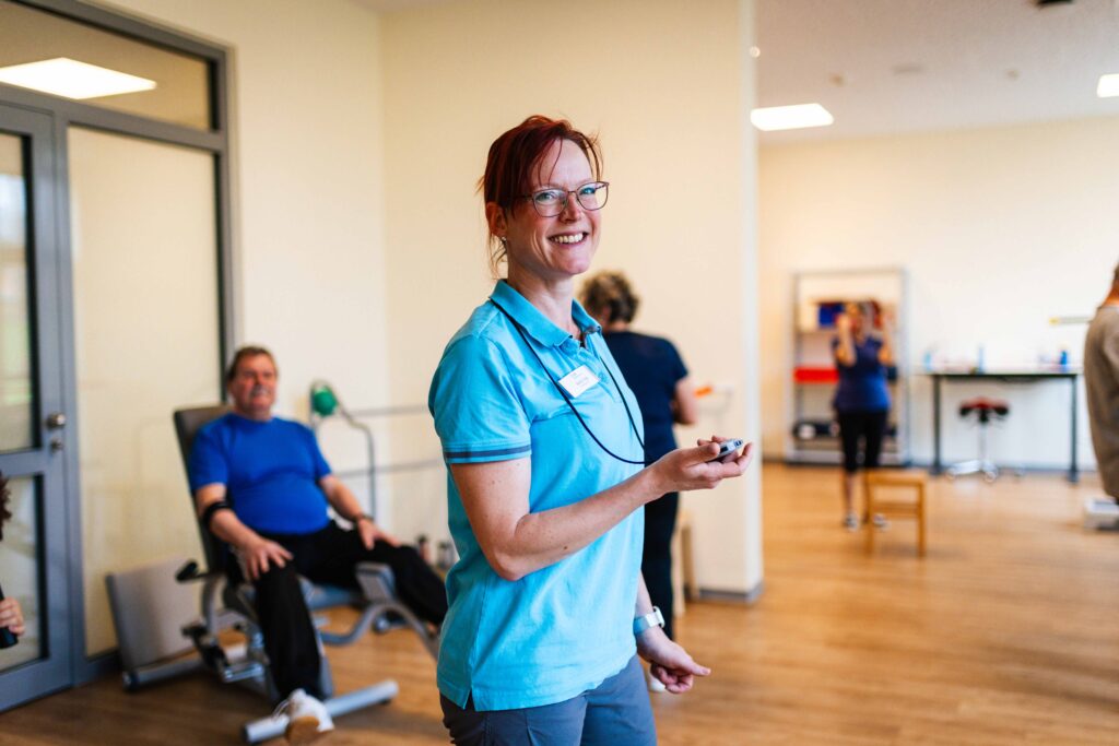 Lächelnde Physiotherapeutin im hellen Trainingsraum einer Rehaklinik